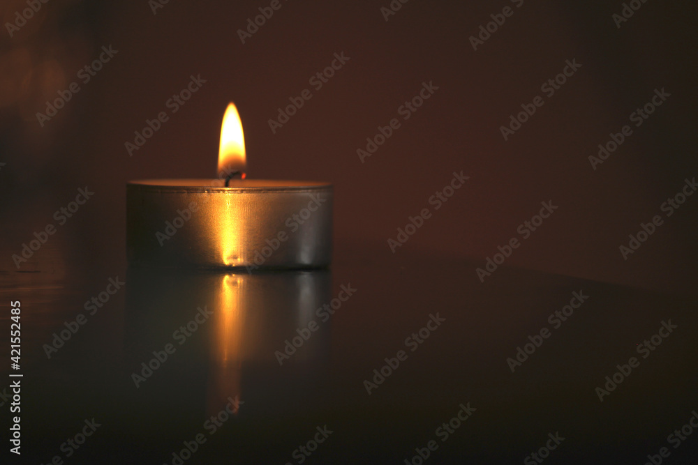One golden burning candle in the middle of blured background and bokeh, decorations for warm cozy interior, warmth and romanic atmosphere One golden burning candle in the middle of blured background and bokeh, decorations for warm cozy interior, warmth and romanic atmosphere