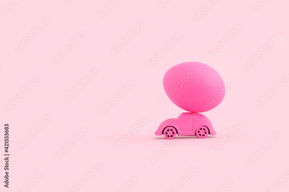 Funny creative Easter concept with toy car and pink egg on top Funny creative Easter concept with toy car and pink egg on top