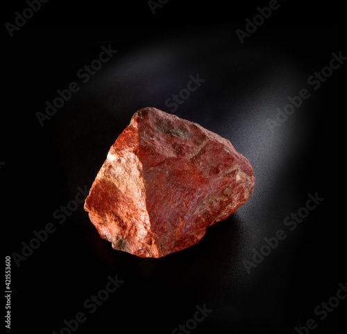 Raw red feldspar mineral nugget from Tian Shan mountains isolated on black background. For geology mineralogy magazines websites article  Natural Science museum wall charts and posters etc
