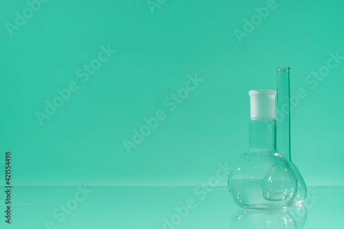 Chemical vessels. Glass flasks. Laboratory utensil. Green background.