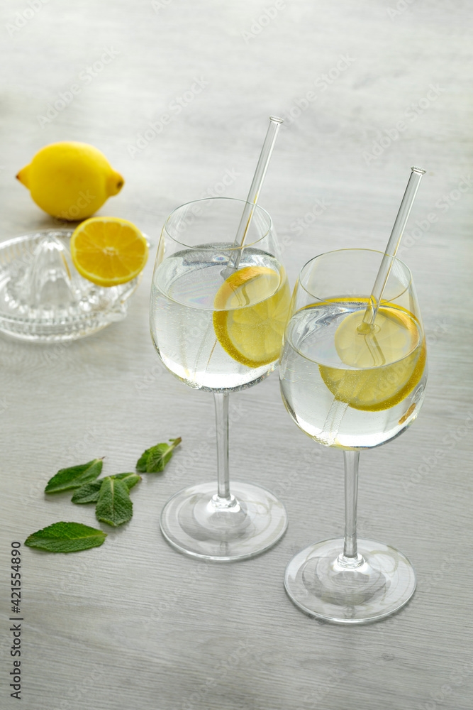 Glasses with water and lemon slice and a citrus press at the background