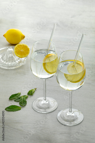 Glasses with water and lemon slice and a citrus press at the background