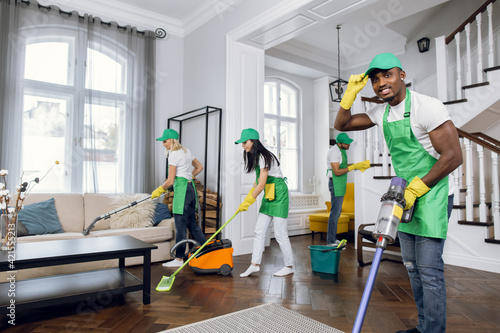 Mixed race janitors doing spring cleaning of house