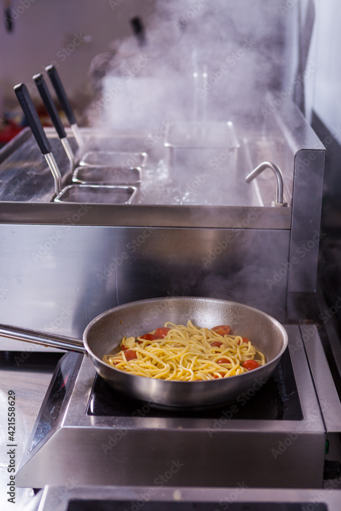 Cooking spaghetti concept. Pasta in the pan. Cooking Fresco Pasta. Italian cuisine, tomato sauce for pasta, healthy food making, detailed view steam in the kitchen. Flipping pasta in the air Cooking spaghetti concept. Pasta in the pan. Cooking Fresco Pasta. Italian cuisine, tomato sauce for pasta, healthy food making, detailed view steam in the kitchen. Flipping pasta in the air