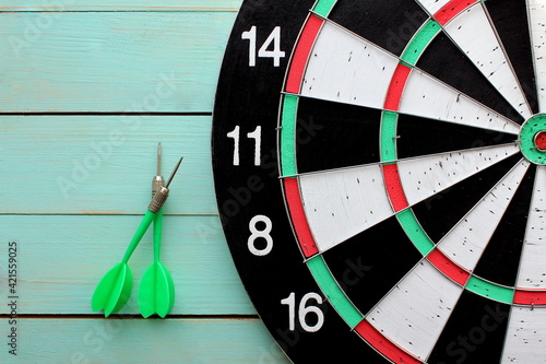  Dart board with two darts lies on a wooden background