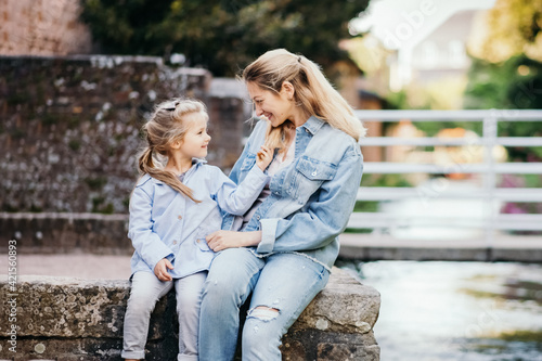 Mother and daughter sit by the river and laugh