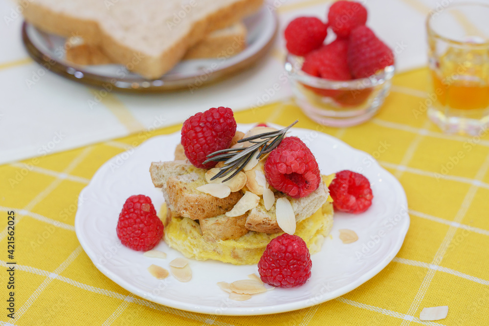 Homemade sweet bread pudding dessert with honey and raspberries in white dish on yellow table blackground. Homemade sweet bread pudding dessert with honey and raspberries in white dish on yellow table blackground.