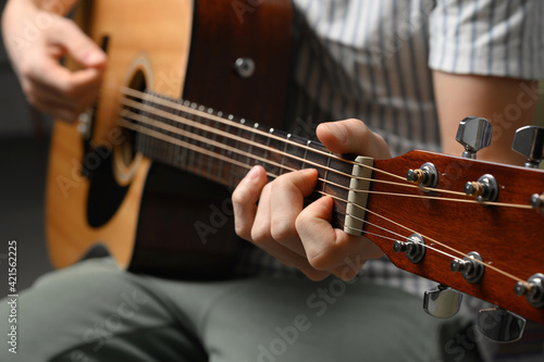 Man playing acoustic guitar, cover for online courses, learning at home.