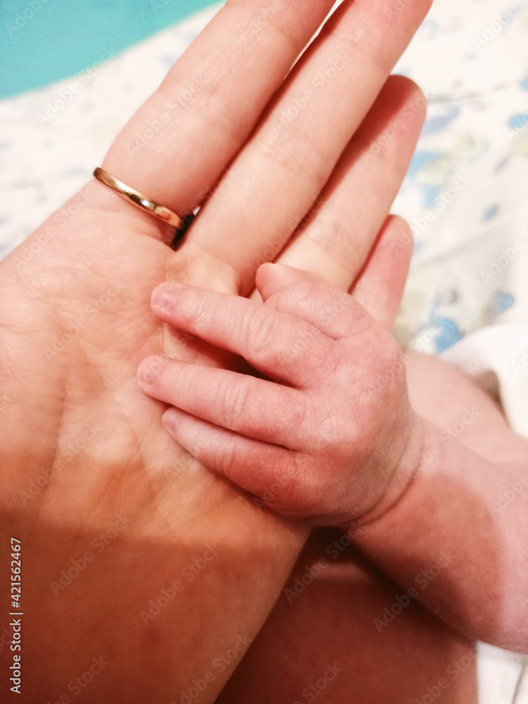 The hand of the newborn baby is in the palm of the mother