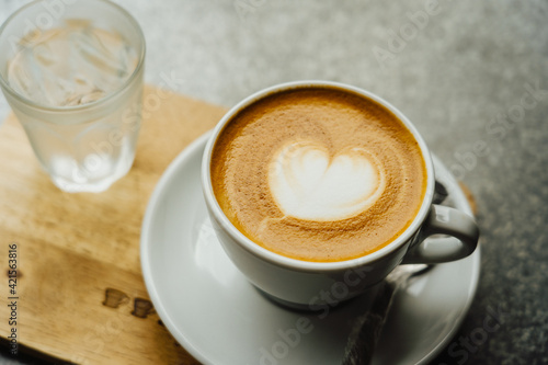 White coffee cup of heart shape latte art on wood table background.