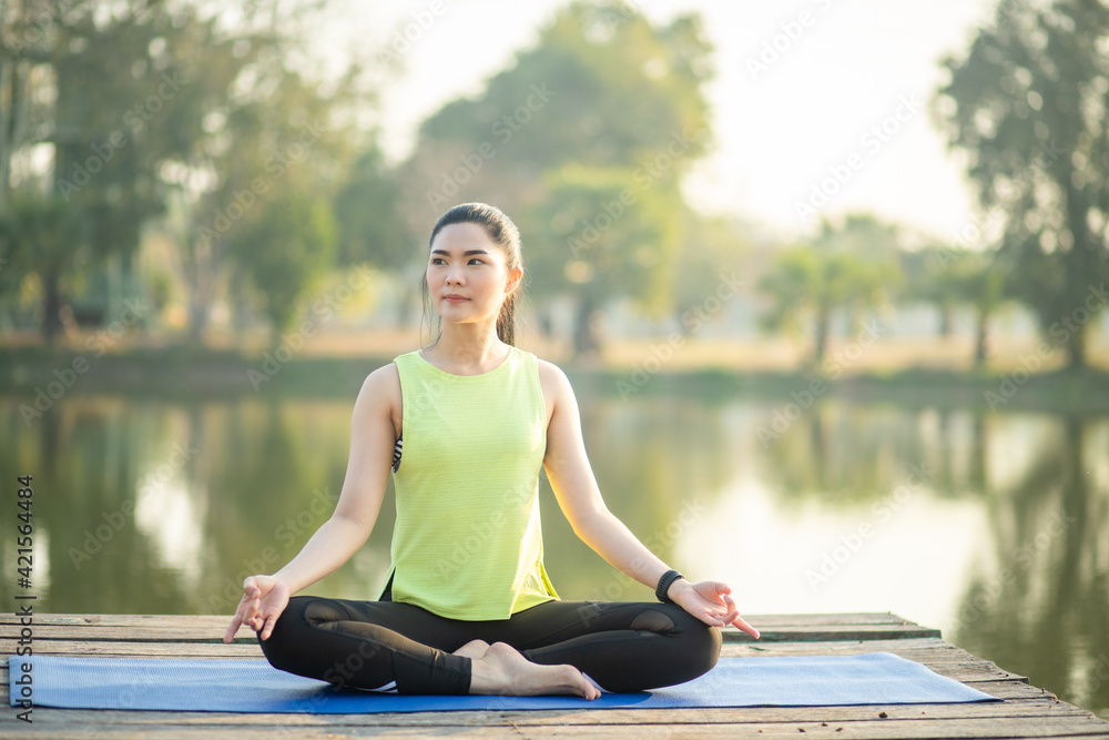 Young woman practicing yoga, breathing, meditation in lotus pose on a yoga mat