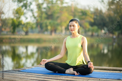 Young woman practicing yoga, breathing, meditation in lotus pose on a yoga mat © atsarapong