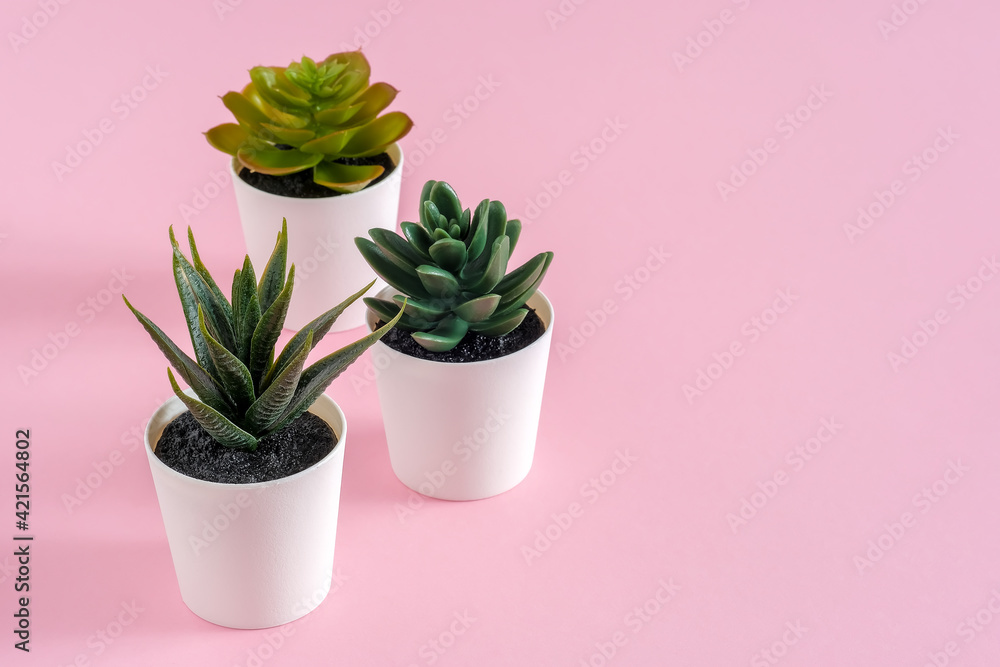 Three artificial green flower with leaves in a pot on pink pastel background, copy space