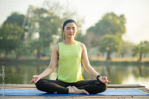 Young woman practicing yoga, breathing, meditation in lotus pose on a yoga mat © atsarapong