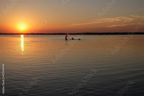 Happy family resting on the lake. Make splashes of water around. Human silhouettes on sunset background. Lake Svityaz, Ukraine. Copy space. 
