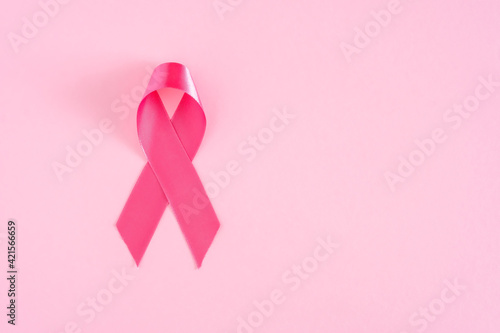 Pink ribbon on pink pastel background, top view with copy space for text. Breast cancer awareness concept