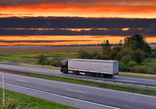 Trucks with Semi-trailer driving on highway on sunset background. Goods Delivery. Services and Transport logistics.