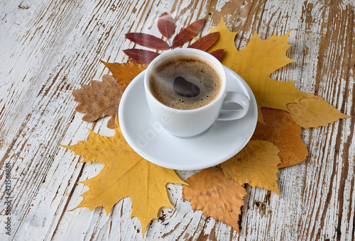 Сup of coffee with autumn leaves on table.