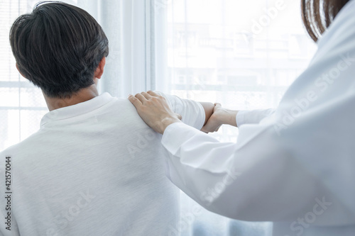 Female doctor hand doing physical therapy By extending the shoulder of a male patient