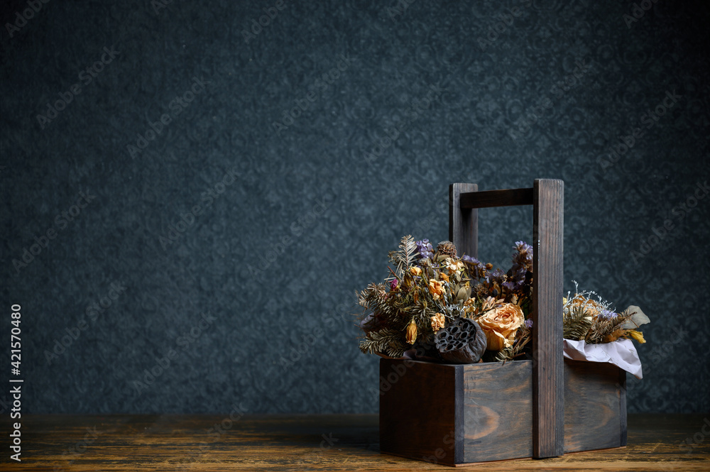 Fototapeta premium Composition of dried flowers in a wooden basket on dark background