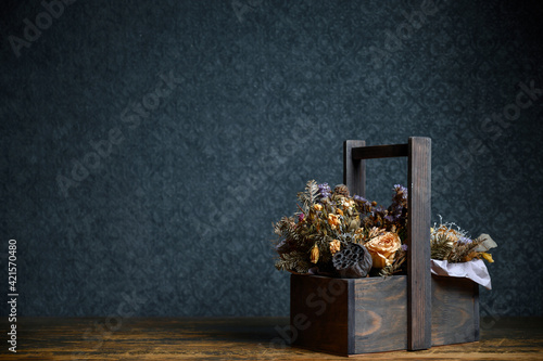 Composition of dried flowers in a wooden basket on dark background