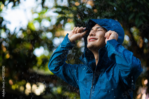 Foto Young Asian man in raincoat in the outdoor with rain and clouds.