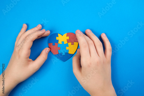 World Autism Awareness day, mental health care concept with puzzle or jigsaw pattern on heart with child's hands