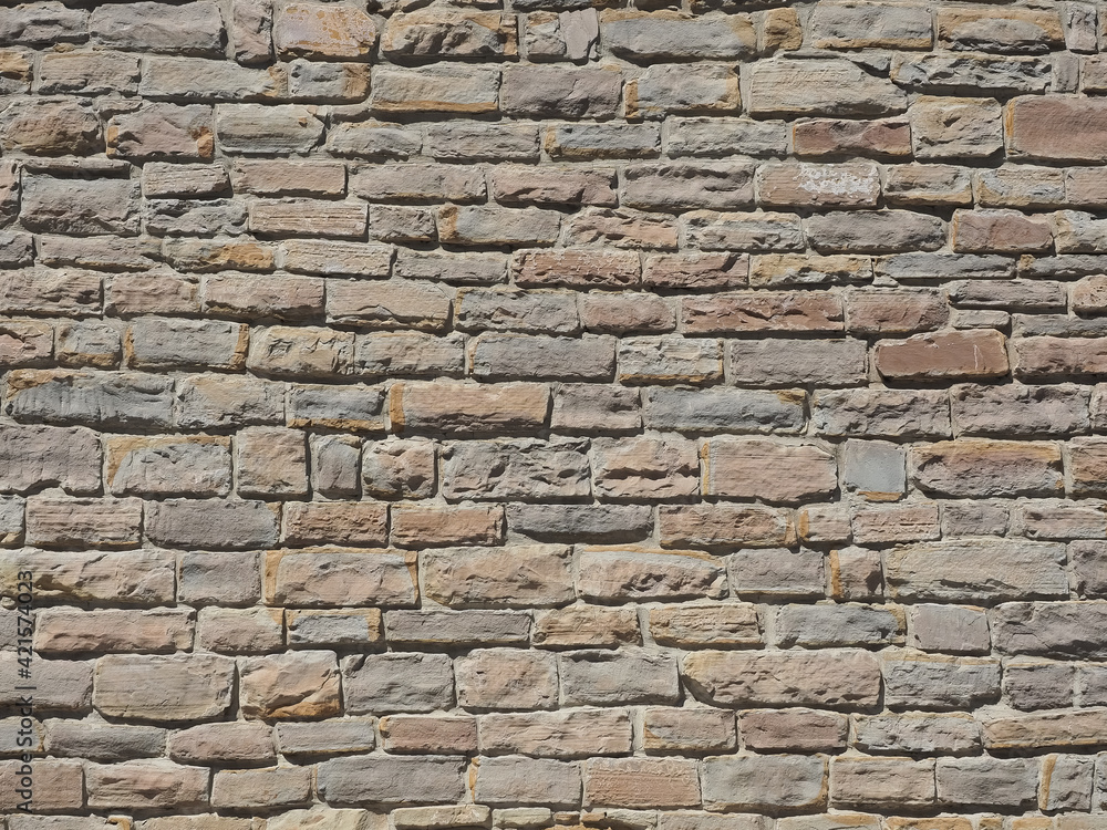A wall with rough and grungy masonry of different sizes illuminated by sunlight. Not seamless texture