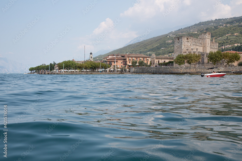 Naklejka premium Panorama Ansicht von Torri del Benaco am Gardasee, Provinz Verona und Blick auf die mittelalterliche Scaligerburg und die vielen Restaurants, Bars und Cafés und Terrassen mit Seeblick