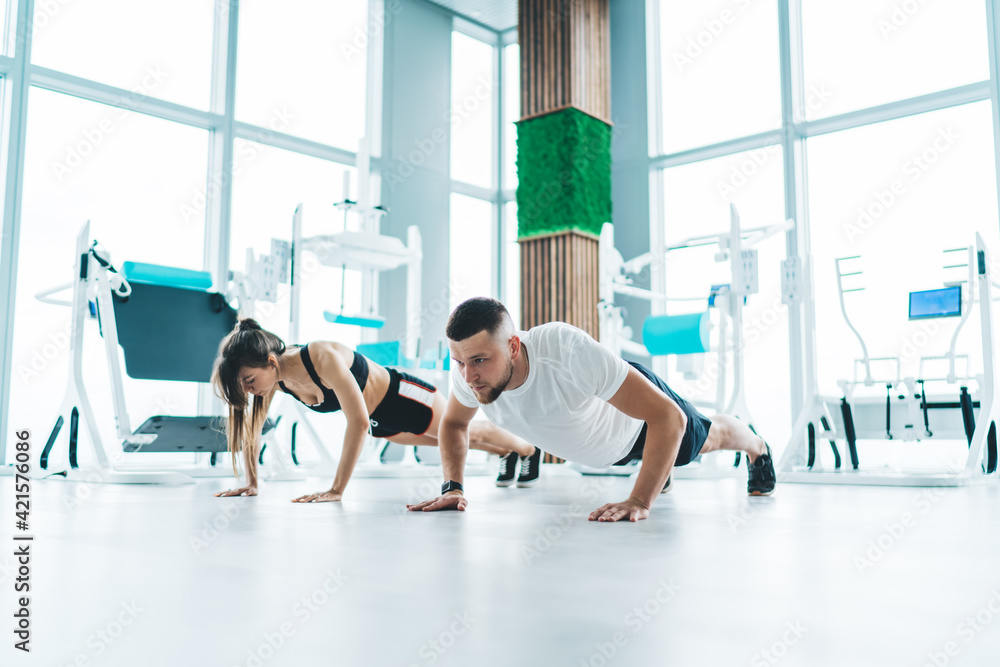 Young active couple doing push ups in gym Young active couple doing push ups in gym