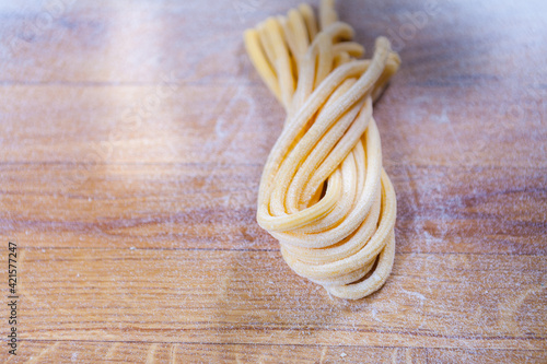 Italian tagliatelle pasta made by hand. Home made spaghetti on the flour table. fresh pasta. Macro Pasta Background. Italian kitchen. Flour egg ingredients. Italian Food