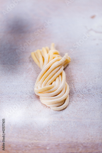 Italian tagliatelle pasta made by hand. Home made spaghetti on the flour table. fresh pasta. Macro Pasta Background. Italian kitchen. Flour egg ingredients. Italian Food
