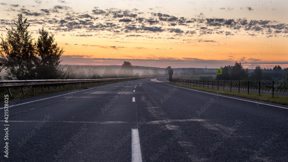 The road going into fog towards the rising sun