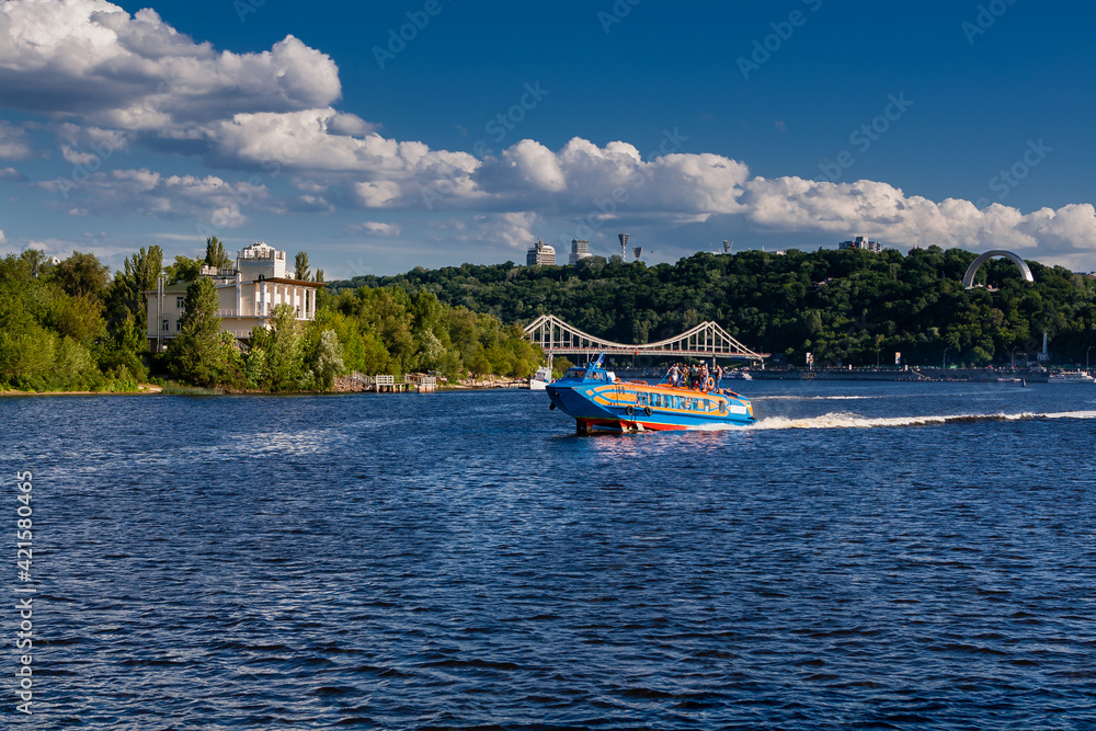 Fototapeta premium Speedboat sails on the river against the beautiful sky