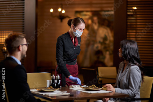Friendly restaurant staff using mask and gloves for protection