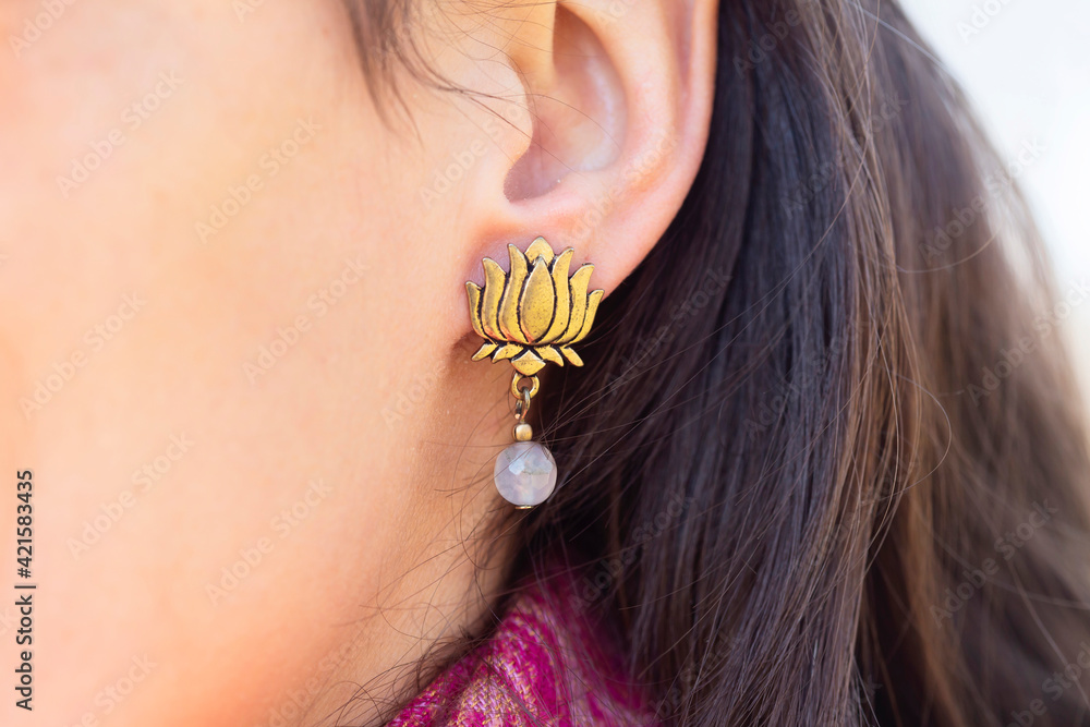 Detail of female ear wearing stone mineral floral shape bead earring