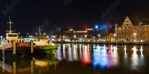 ships on the river with reflections of lights, in the background an old building and a new office building  © Robert