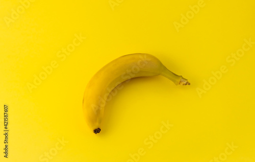 one yellow banana lies on a yellow background