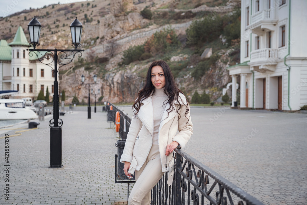 Fototapeta premium A woman in beige clothing enjoying the view of the sea on a warm, windy day.