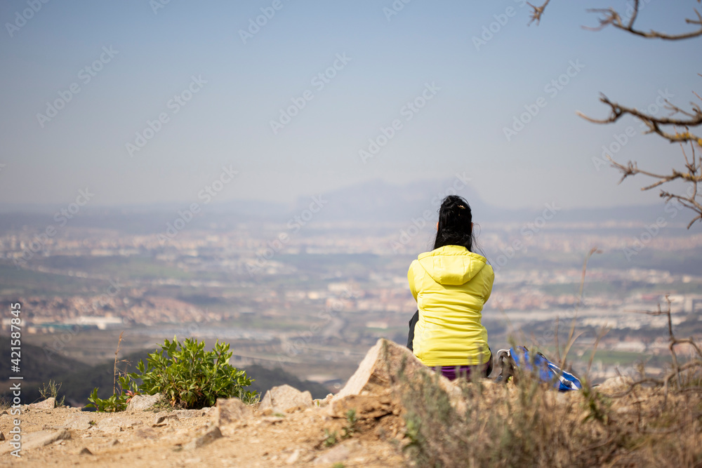 Girl sitting on the mountain looking at the landscape.