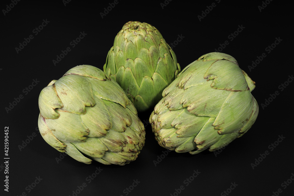 Still life with three fresh artichokes on black background Still life with three fresh artichokes on black background