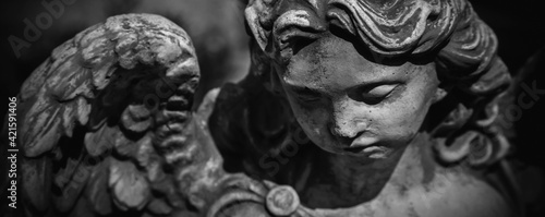 Close up sad guardian angel. Fragment of an ancient statue. Horizontal image.