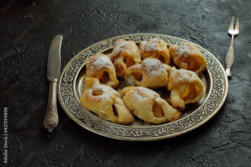 Small homemade pies with apples on a dark table. Daylight. Selective focus Small homemade pies with apples on a dark table. Daylight. Selective focus