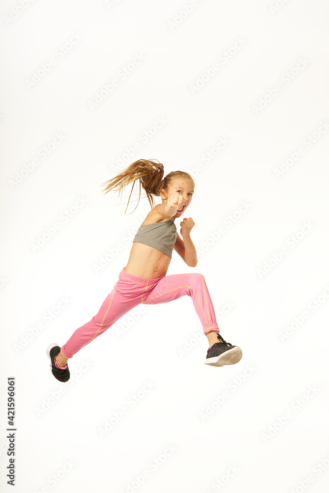 Adorable sporty girl jumping and punching air