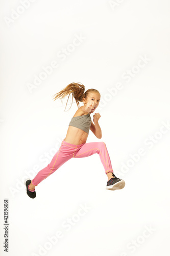 Fototapeta Naklejka Na Ścianę i Meble -  Adorable sporty girl jumping and punching air