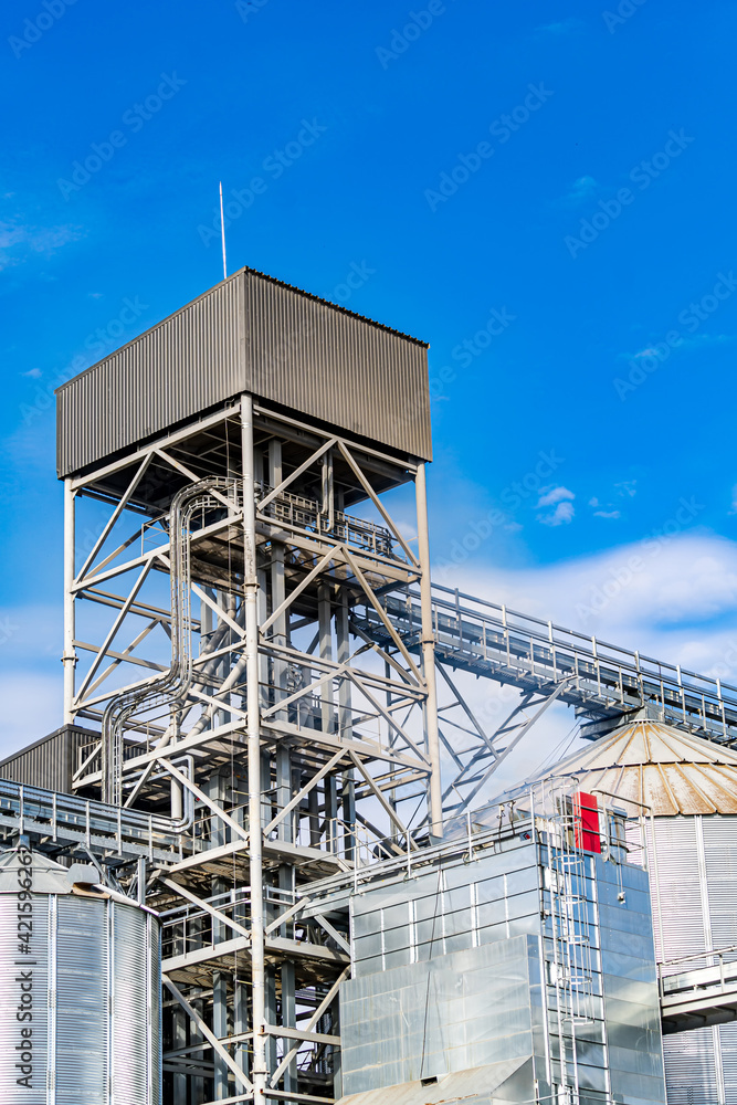 Big construction tower in large factory. Metallic tower on blue sky. Large warehouse. Big construction tower in large factory. Metallic tower on blue sky. Large warehouse.