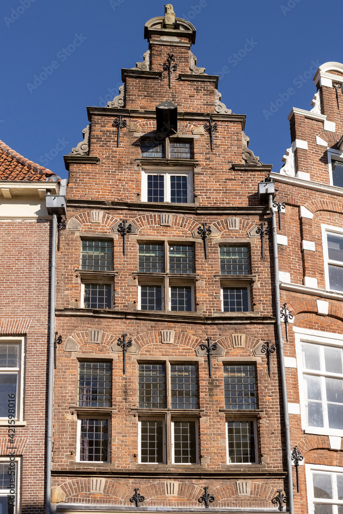 Frontal view of a historic medieval mansion exterior facade in Hanseatic city center Zutphen, The Netherlands, against a clear blue sky with typical gable shape. Europe tourism destination.