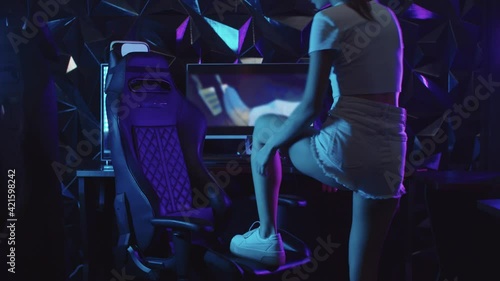 Girl gamer putting her leg on the chair in the gaming club and tieing up her shoe  photo