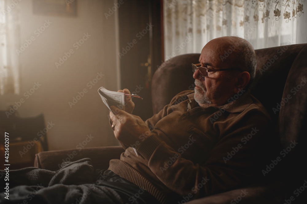 Senior man  with crossword at home