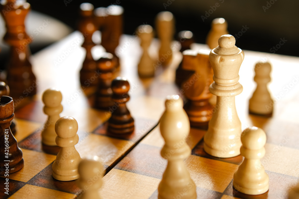 White and brown wooden chess pieces on board game. White and brown wooden chess pieces on board game.